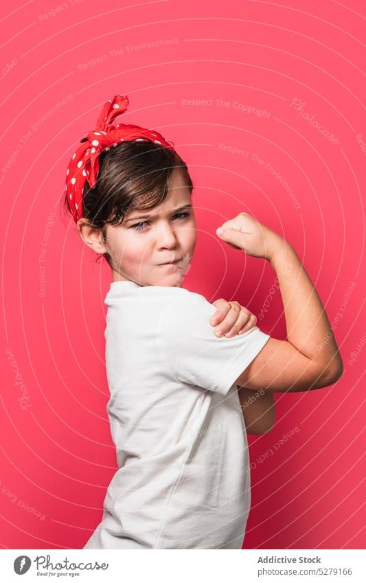 Cute powerful little girl showing muscles bicep strong feminist headband polka dot studio shot adorable kid child colorful demonstrate cute energy right
