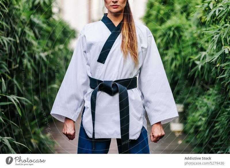 Anonymous professional TKD master standing on street woman self assured path confident taekwondo sport karate belt athlete uniform fighter activity strong