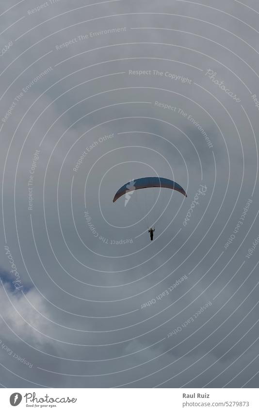A person paragliding on a cloudy day adrenalin action crazy flight fly free freedom jump recreation risk speed wind wing extreme hang high pilot skydiving sport
