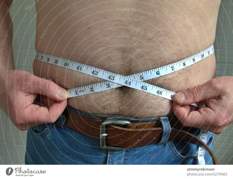 Man's waistline being measured person man weight normal loss measuring tape health overweight BMI obese body lifestyle diet fitness health care stomach male fat