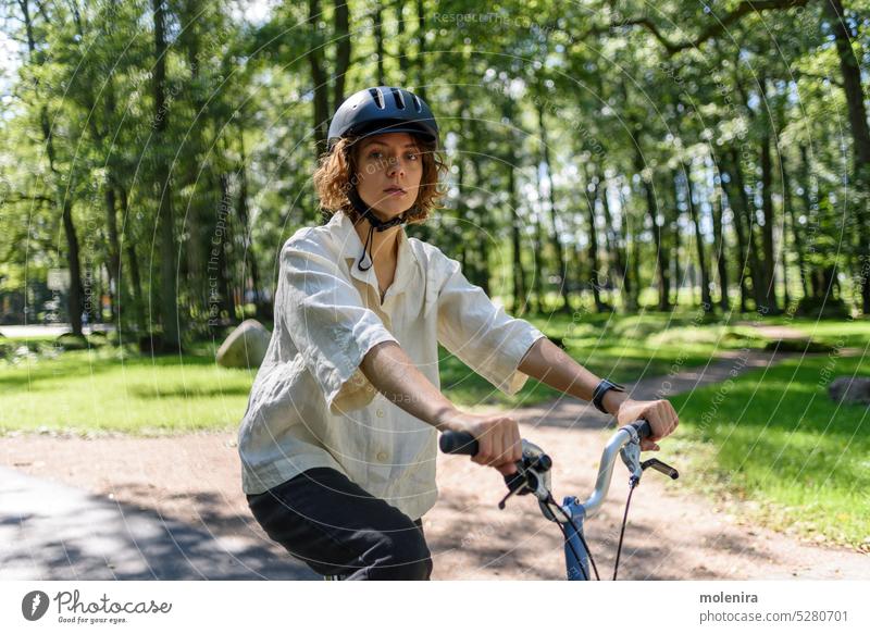 Woman riding on bicycle at city woman female activity helmet lifestyle citizen artist romance summer enjoying individuality beauty 30s park sunny action