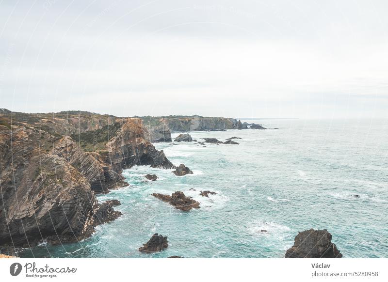 Rugged rock and cliff coastline on the Atlantic Ocean near the town of Zambujeira Do Mar in the west of Portugal in the famous tourist region of the Algarve. Daylight