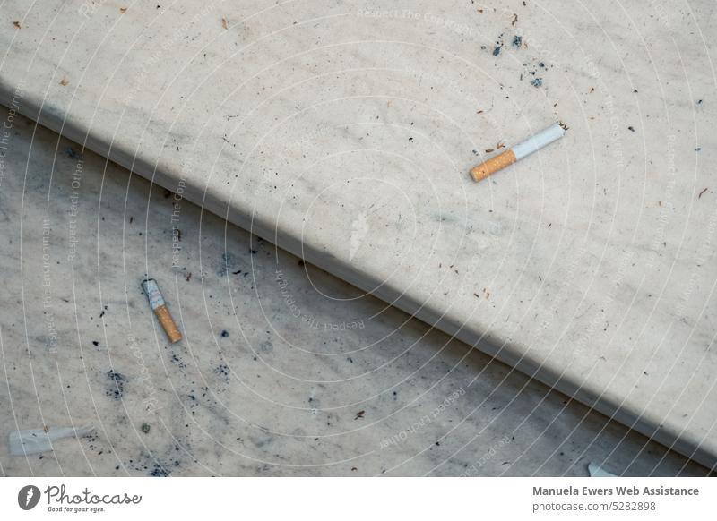 Close up of cigarettes lying around on stairs in run down shopping center Addiction drugs Nicotine Trash waste polluted Dirty Stairs Shopping malls waiting area