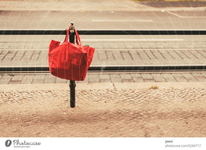 Red shopping bag forgotten Bag Pouch Hang Street Forget demarcation Fence Lanes & trails Barrier Border Traffic infrastructure Retro Town Cobblestones Sidewalk