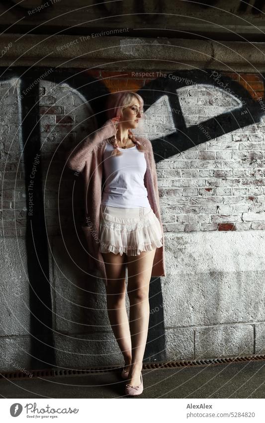Young woman with pink blonde hair stands in front of brick wall in tunnel with graffiti Woman Brick Wall (building) Graffiti portrait Eyeglasses pretty Slim