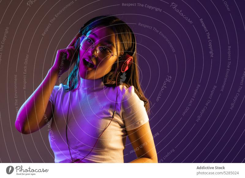 Young woman wearing headphones while listening to music confident young gadget meloman modern song melody cool individuality vibrant millennial outfit casual