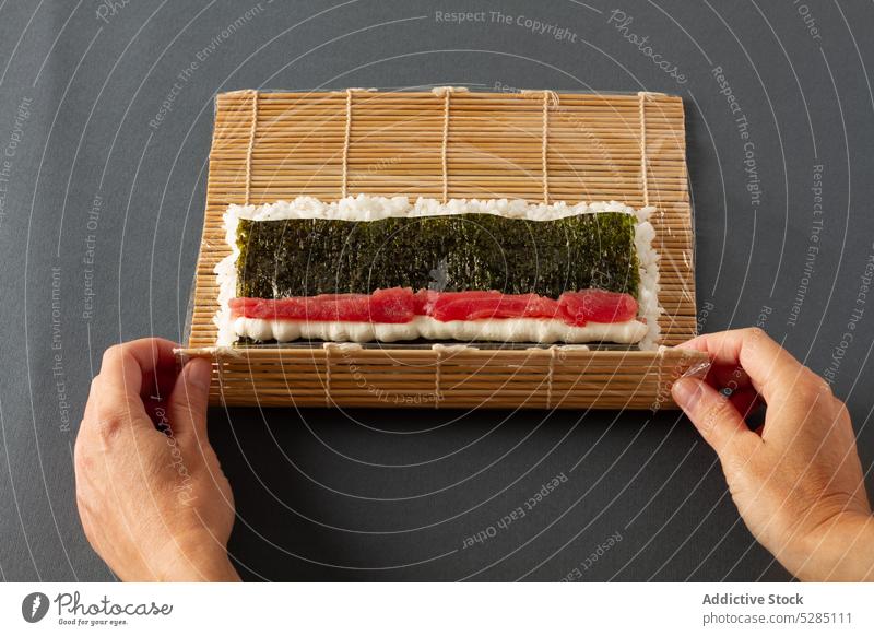 Crop person rolling maki sushi hand seaweed rice salmon asian food cuisine mat healthy fish tasty bamboo tradition prepare culture culinary ingredient process