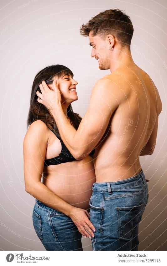 Happy couple expecting baby embracing in studio pregnant touch hair embrace await studio shot love care relationship smile happy peaceful young underwear