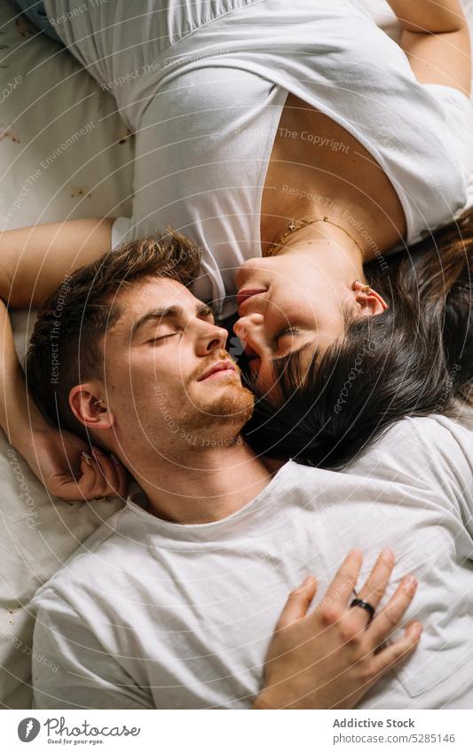 Loving couple lying on bed eyes closed care affection gentle love peaceful boyfriend girlfriend sensual calm tranquil young romantic partner at home bonding
