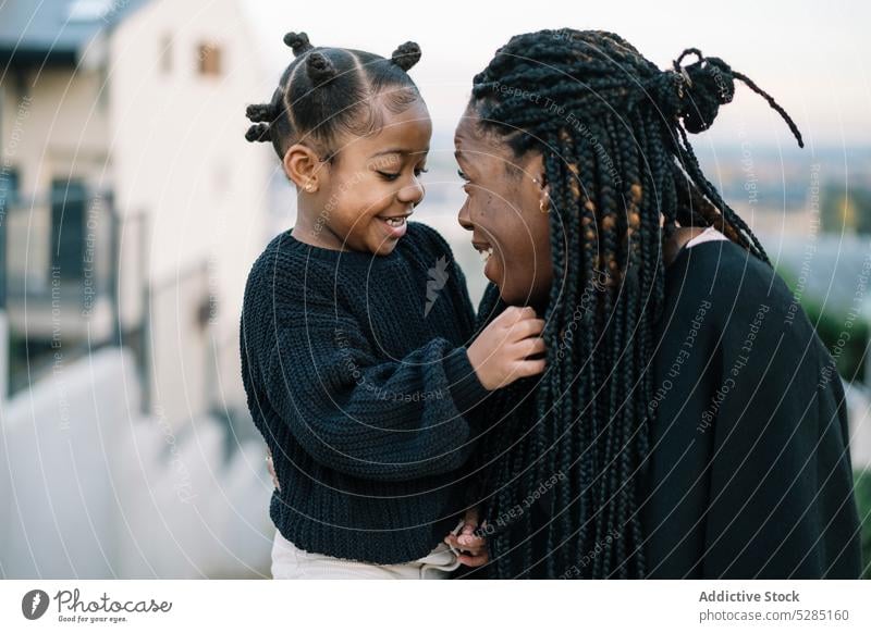 Happy black mother and daughter hugging outdoors woman girl match support care bonding smile street tender happy female cuddle kid child african american ethnic