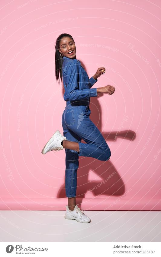 Excited black woman jumping in studio model style trendy fashion happy outfit excited cheerful young female african american ethnic positive smile joy