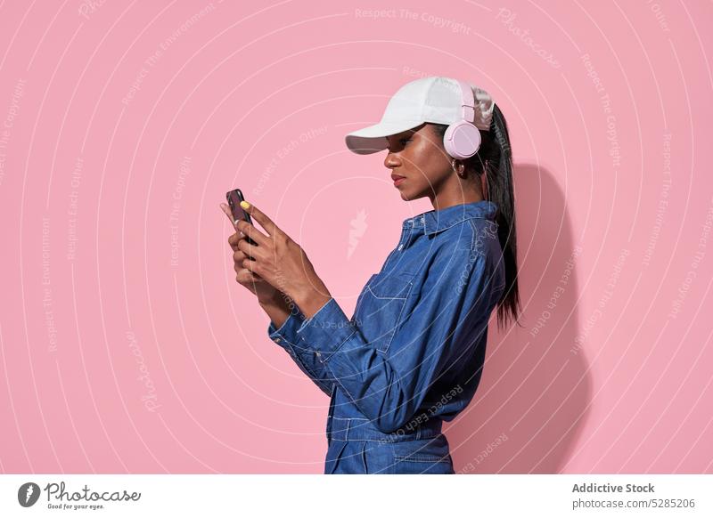 Serious black woman in headphones messaging on smartphone surfing browsing listen internet fashion confident serious style african american female gadget young