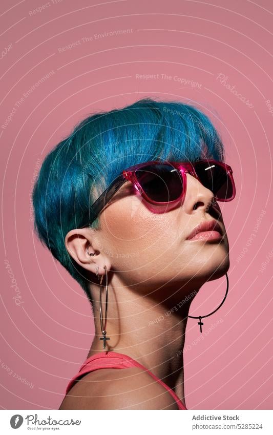Stylish young woman with blue hair model studio shot sunglasses dyed hair individuality personality unemotional emotionless female top stand bright unique