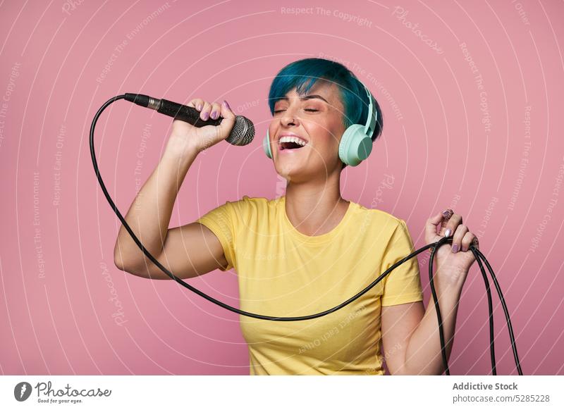 Cheerful woman in headphones singing into microphone song listen music entertain voice active cheerful fun joy expressive female young sound audio melody