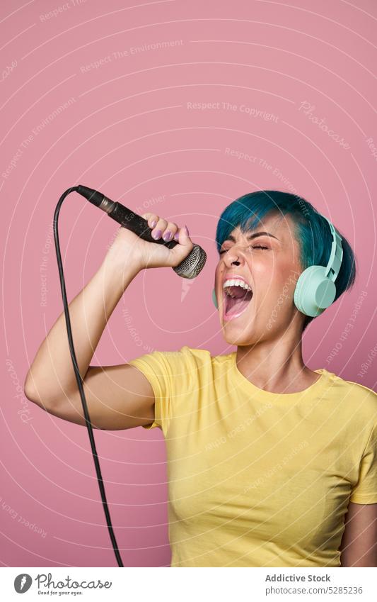Cheerful woman in headphones singing into microphone song listen music entertain voice active cheerful fun joy expressive female young sound audio melody