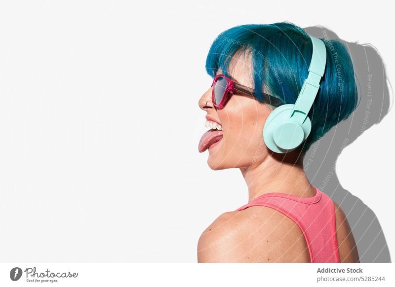 Cool woman in headphones sticking tongue out gesture listen music entertain active cool fun joy expressive female young sound energy pastime having fun