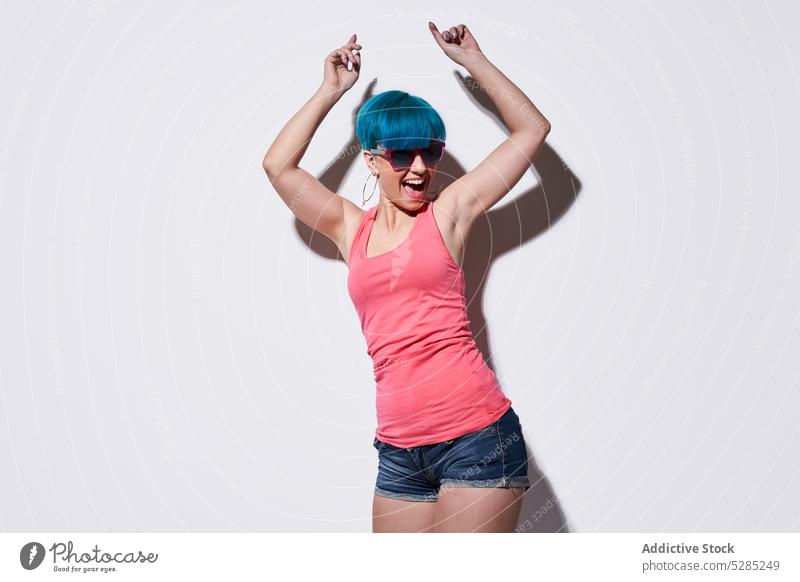Cheerful woman with blue hair dancing in studio dance arms raised excited having fun active studio shot cheerful unique joy smile positive happy expressive