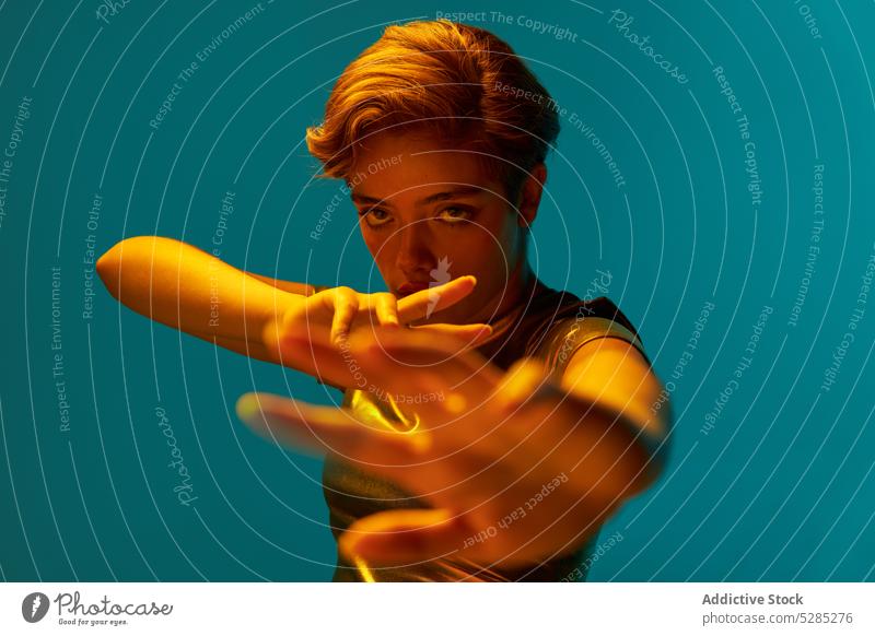 Serious young woman with raised arms serious concentrate show demonstrate warrior focus gesture studio shot style wall calm female short hair golden stand