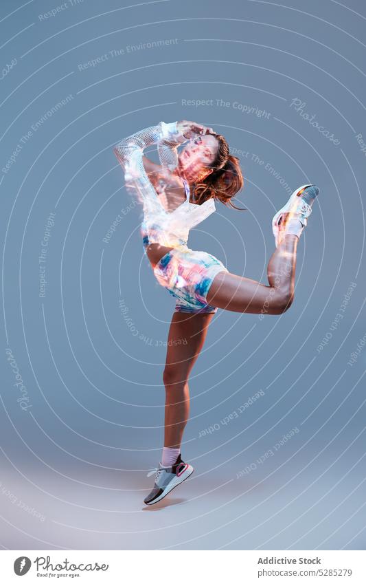Fit woman dancing in studio dance jump energy arms raised perform projector light move active studio shot fit sporty perfect body young dancer emotionless