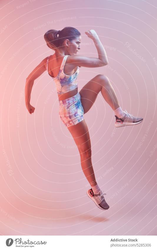 Stylish sportswoman jumping on pink background - a Royalty Free