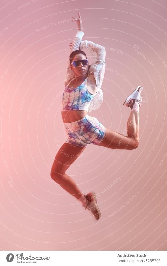 Fit woman jumping in studio dance energy arms raised move active studio shot sunglasses fit sporty perfect body young dancer female lady healthy figure minimal