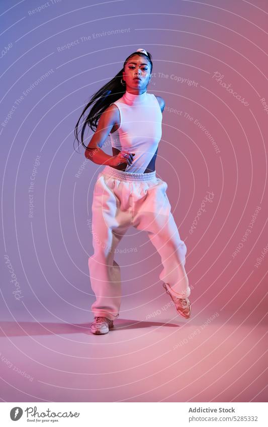 Energetic mixed race woman dancing in studio with neon illumination dancer skill practice action studio shot female lady young ethnic style flexible modern