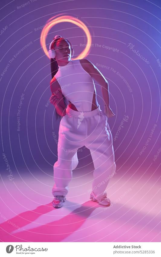Mixed race woman dancing in studio listening to music on headphones dancer studio shot emotionless eyes closed song young mixed race ethnic female bodysuit