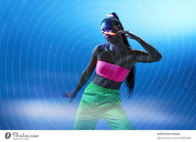 Mixed race female dancing in studio with blue neon illumination woman dancer practice action projector perform studio shot hobby active lady young mixed race