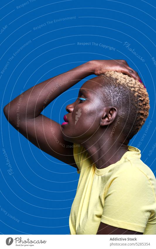 Confident black woman touching hair against blue background style makeup color portrait model fashion appearance bright vivid colorful dreamy african american