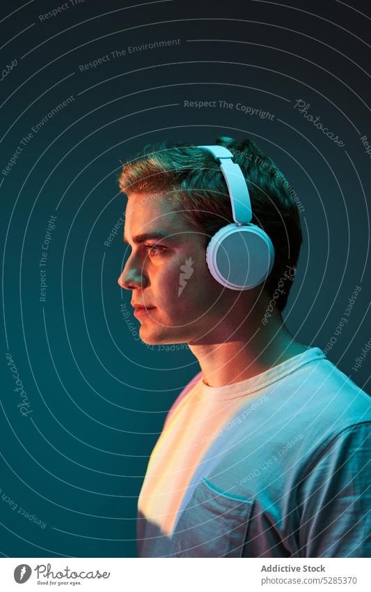 Man listening to music in headphones man neon relax wireless calm illuminate portrait male young sound song modern audio casual glow gadget device cool melody