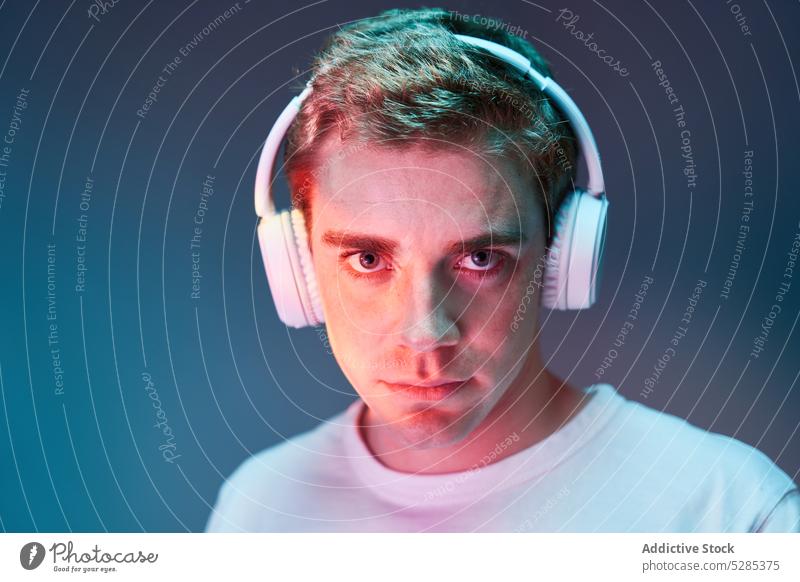 Man listening to music in headphones man neon relax wireless calm illuminate portrait male young sound song modern audio casual glow gadget device cool melody