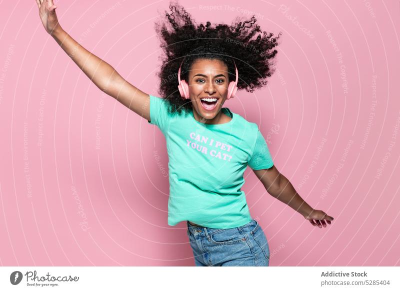 Excited black woman jumping and smiling music listen happy headphones energy smile style colorful female young african american ethnic joy cheerful casual