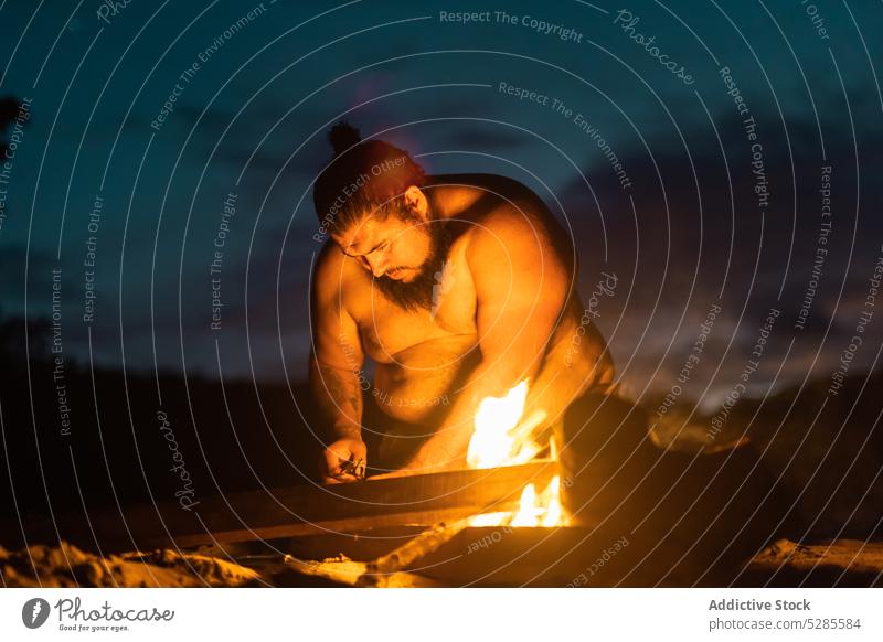 Obese man preparing for burning fire bonfire shirtless beach night obese prepare relax coast shore sky nature male cloudy rest sit dark evening seashore