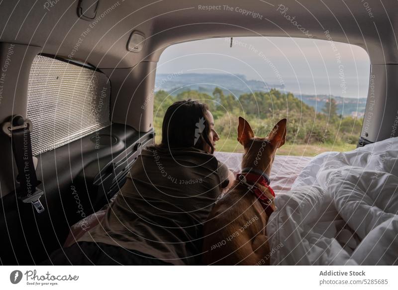 Woman and dog lying on mattress in car woman traveler pet relax rest admire scenery vacation picturesque female obedient animal mountain companion spain