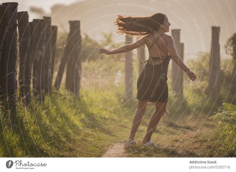 Carefree young ethnic woman spinning around on pathway in nature at sundown spin around dance happy sunset smile tourist holiday enjoy carefree vacation meadow