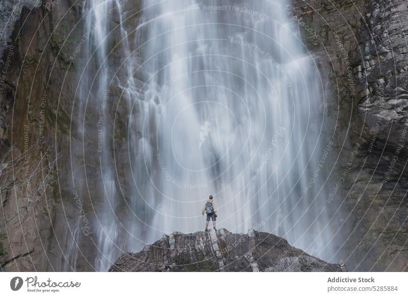 Anonymous man standing near waterfall cascade traveler tourist city outstretch nature backpacker freedom carefree explore male adventure huesca city spain