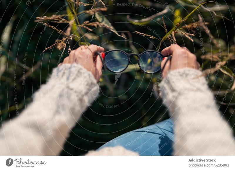 Unrecognizable woman with eyeglasses in hands forest nature relax calm sweater summer environment countryside weekend tranquil peaceful harmony idyllic serene