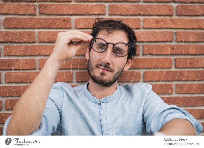 Thoughtful man with glasses against brick wall pensive thoughtful hipster confident beard serious sit eyeglasses casual male think shirt concentrate style young
