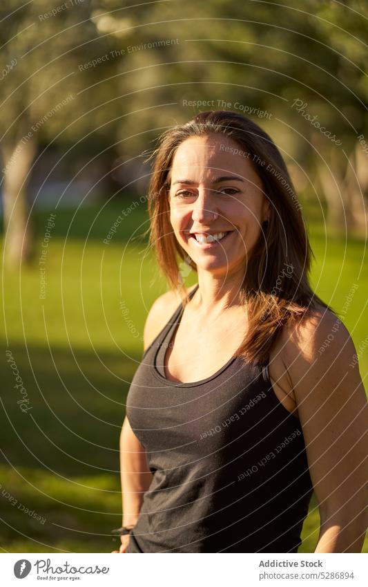 Cheerful athletic woman in sunny park athlete cheerful portrait smile sportswear summer training fitness positive wellbeing sportswoman confident content