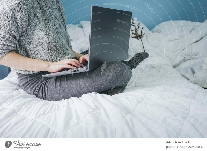 Anonymous female freelancer using computer on bed woman laptop self employed browsing independent typing chat project gadget online connection bedroom lady