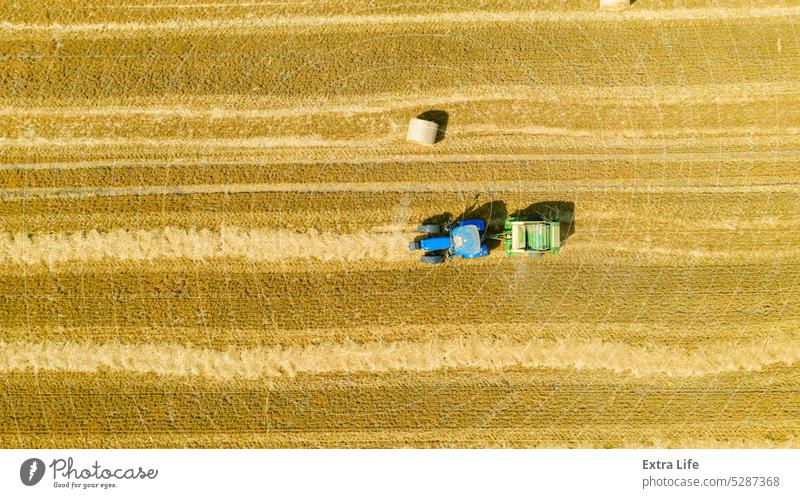 Aerial view of tractor tow trailed bale machine to collect straw from harvested field Above Agricultural Agriculture Arable Bale Baler Baling Cereal Compact