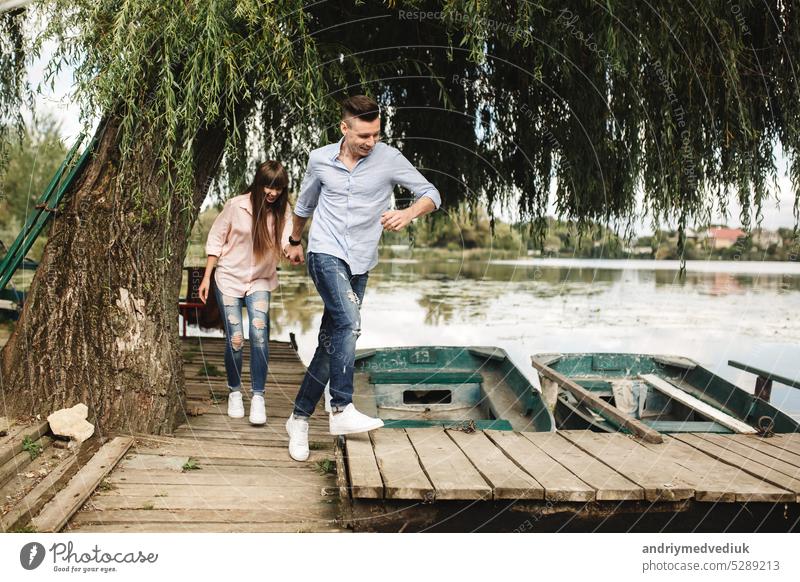 Happy young couple outdoors. young love couple running along a wooden bridge holding hands. boyfriend travel girlfriend summer happiness nature flirting fun