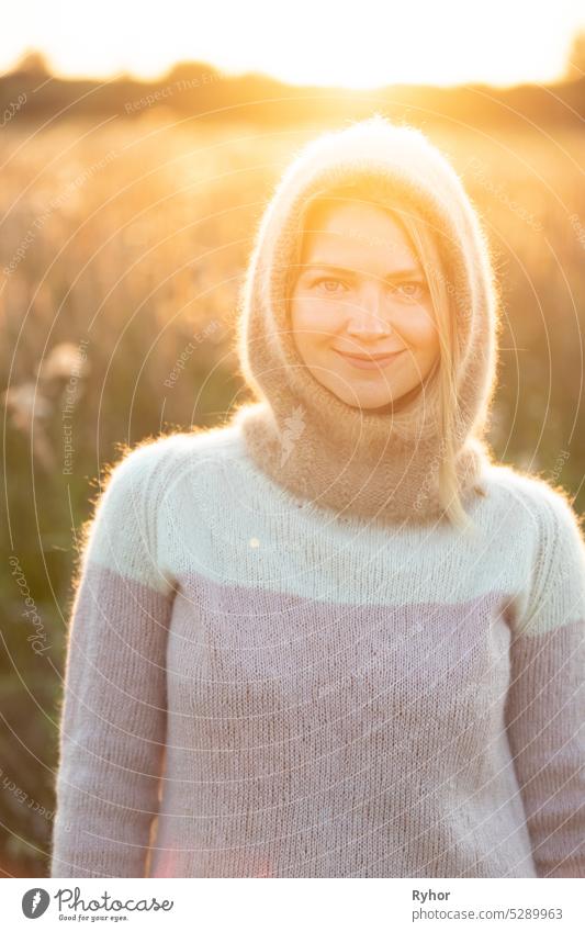 Portrait Of Young Pretty Caucasian Happy Girl Woman In Woolen Jacket Blouse And Brown knitted bonnet Posing In Early Spring Forest In Sunny Day. Enjoy Outdoor Nature. beautiful young woman smiling. power of women. knitted wear, knitted bonnet, knitwear