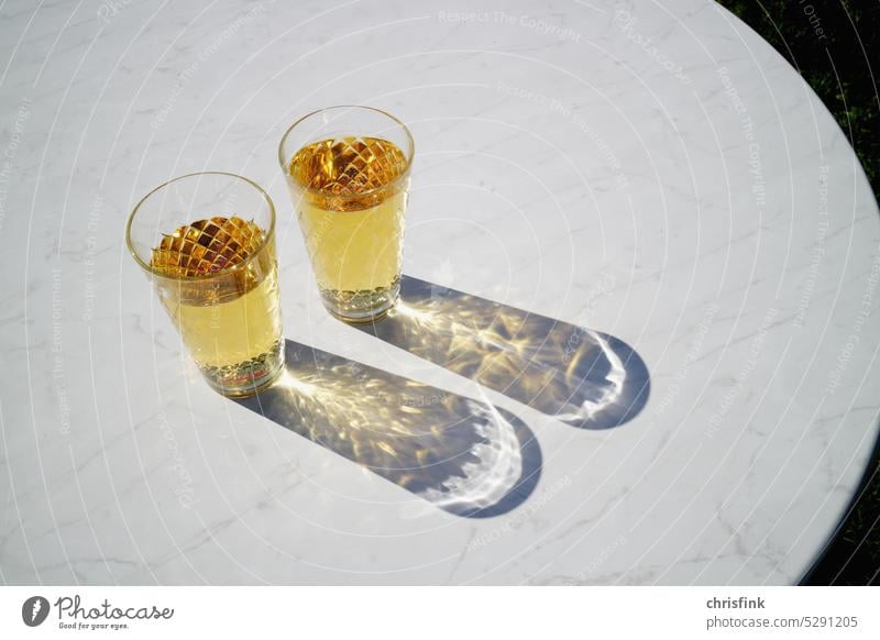 Apple cider glasses stand in sun on white table and cast shadow Glass Vine Apple Cider Äppler squirter Acid sprayed Hesse Apple juice Beverage Refreshment