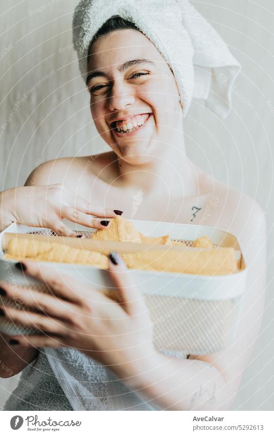 Woman holding basket with different shower supplies. Hands with bright yellow and rolled up towels. Metal mesh storage white basket. Preparing products for a relaxing bath.