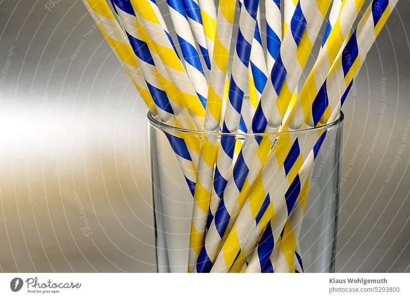 Blue and yellow patterned drinking straws in a glass against neutral background Straw Drinking straws Glass drinking glass Clear glass receptacle Yellow Pattern