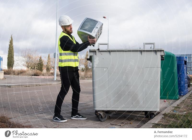 A worker at a recycling plant dumping an old television into a garbage bin. Technology recycling concept. Recycling recycle recycled recyclable