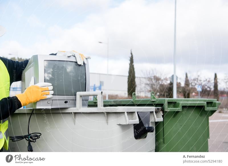 A worker at a recycling plant holding an old television next a garbage bin. Technology recycling concept. Waste management Recycling recycle recycled recyclable