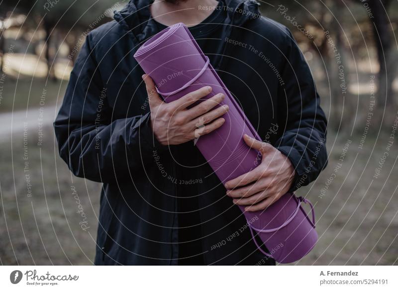 Man holding a purple yoga mat at a park. Concept of doing exerise outside. Man doing yoga. Yoga mat exercise exercise mat violet man boy practise sport