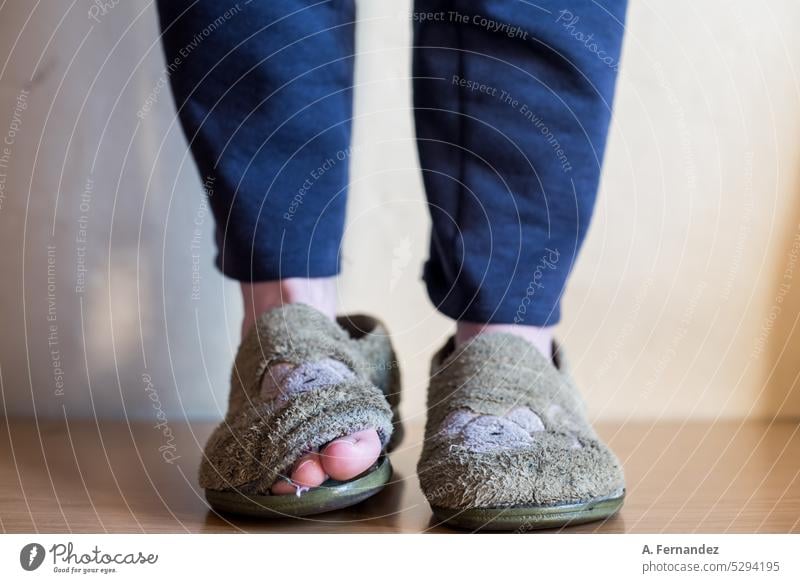 Detail of the feet of a kid wearing old broken and worn house slippers with the toe sticking out. Poverty concept Slippers House slippers Worn out worn-out